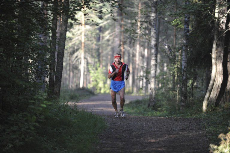 Hardloper boven de 60 tijdens een rustige duurloop op een bospad