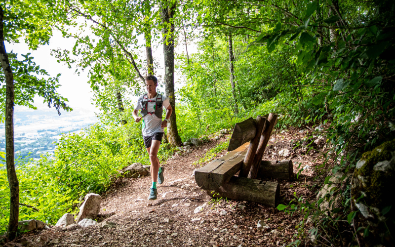 Trailrunner klimt sneller bergop met stokken tijdens klimtraining, praktische trailrunning tips in bergterrein.
