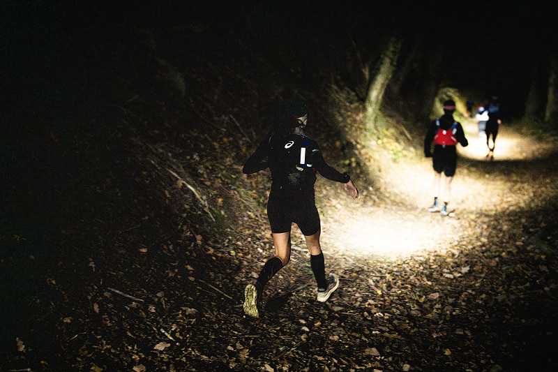 Trailrunner gebruikt sportvoeding tijdens een nachttrail om energie op peil te houden.
